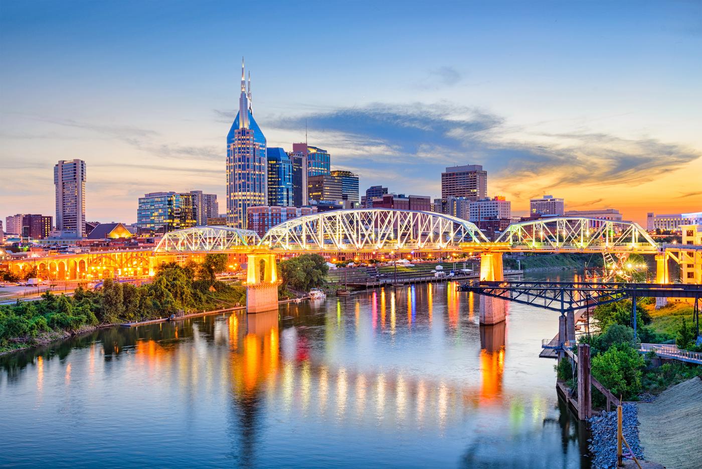 The Nashville, Tennessee skyline at dusk along the Cumberland River, including the AT&T tower and Shelby Street pedestrian bridge, part of the Middle Tennessee business market Schneidman Law serves
